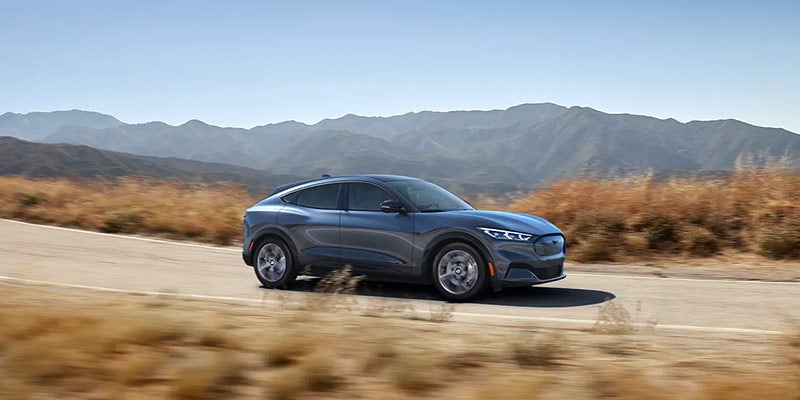 Gray Mustang Mach-E driving on the mountain side road