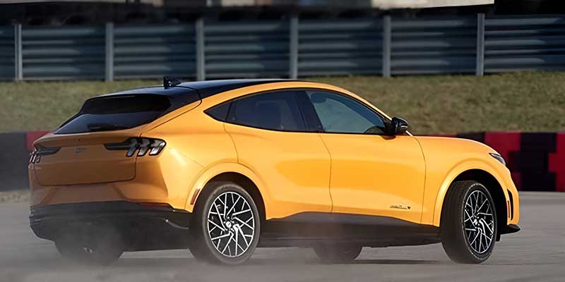 Yellow Ford Mustang Mach-E with dust behind it